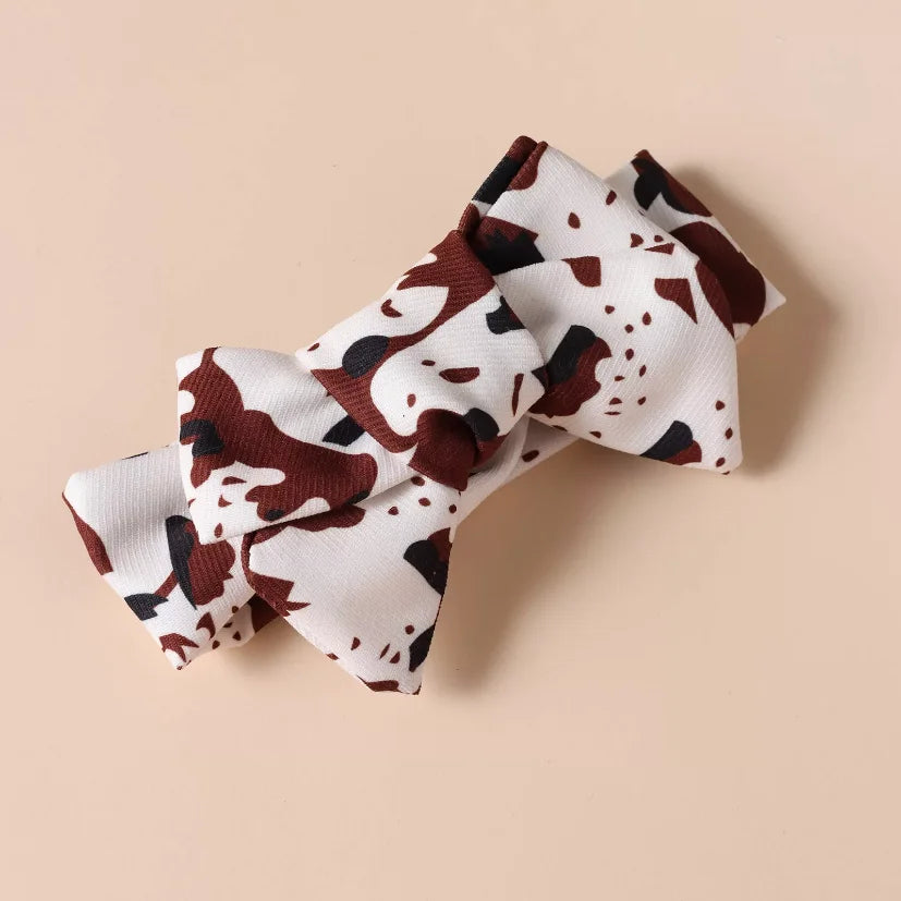 Matching cow print hair bow included in the Girls’ 3-piece Shoulder Flair Shirt and Skirt Set, completing the stylish look with a fun and coordinated accessory.”